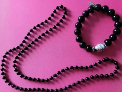 Tradera Svart halsband och armband. Armbandet har en figur och bredvid den stenar.> Halskæder
